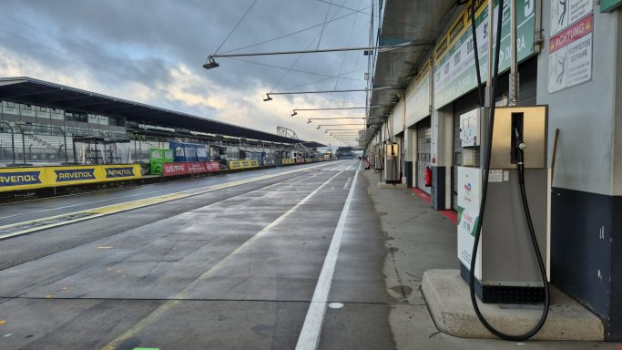 7 Uhr morgens und noch alles ruhig Leere Rennstrecke mit Boxen und Tankstelle, bewölkter Himmel im Hintergrund.