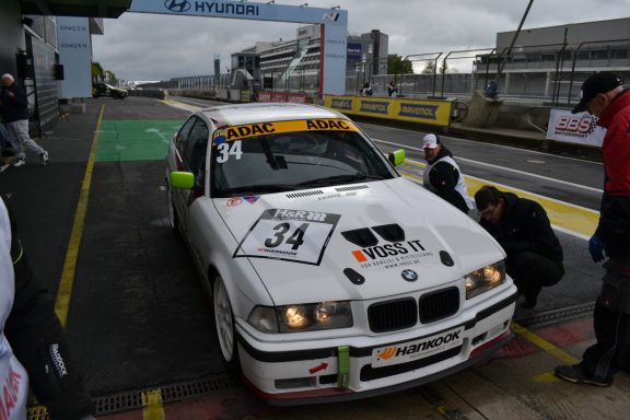 Erster Reifenwechsel BMW-Rennwagen mit der Nummer 34 in der Boxengasse, Teammitglieder arbeiten daran.