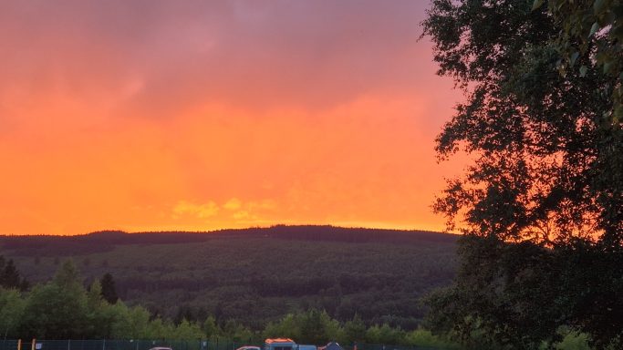 Sonnenuntergang in Spa beim 24h-Rennen Sonnenuntergang über hügeliger Landschaft mit rosa-orangefarbener Himmel.
