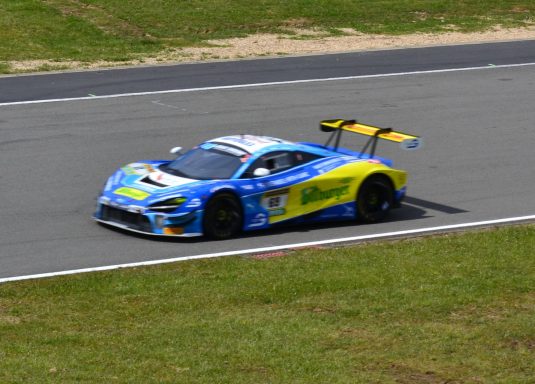 Der McLaren Rennwagen in Blau und Gelb fährt auf einer Strecke.