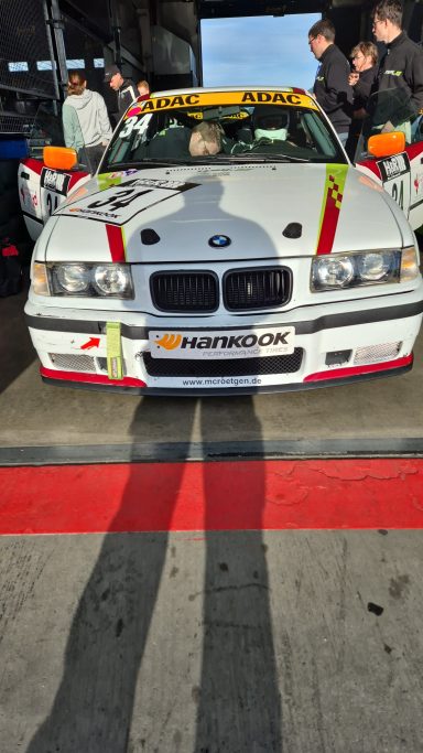 Vorbereitung aufs Qualifying BMW Rennwagen mit leuchtend weißer Karosserie und roten Streifen, im Hintergrund Zuschauer.