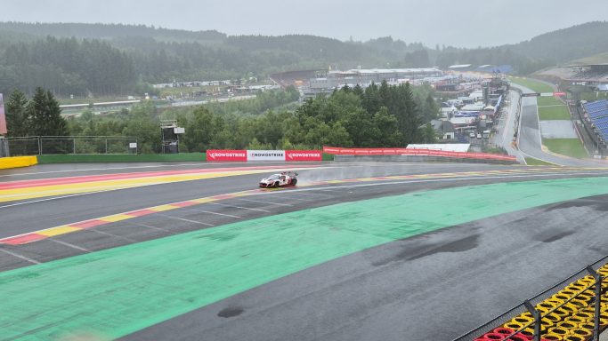 Die Eau-Rouge-Kurve Ein Rennwagen fährt auf einer nassen Strecke bei Regenwetter in Spa-Francorchamps.