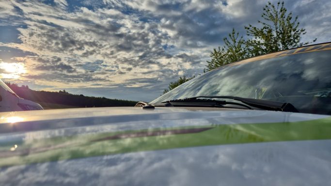 Früh am Morgen am Ring Sicht auf die Motorhaube eines Fahrzeugs mit Sonnenuntergang im Hintergrund.